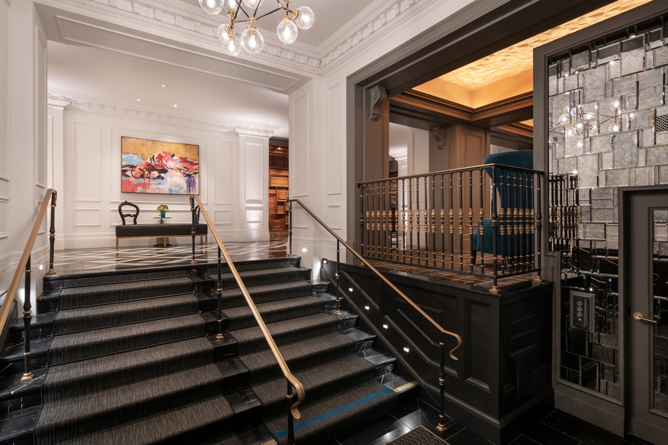 Bright hotel stair hall with black stone steps and classical wall detailing