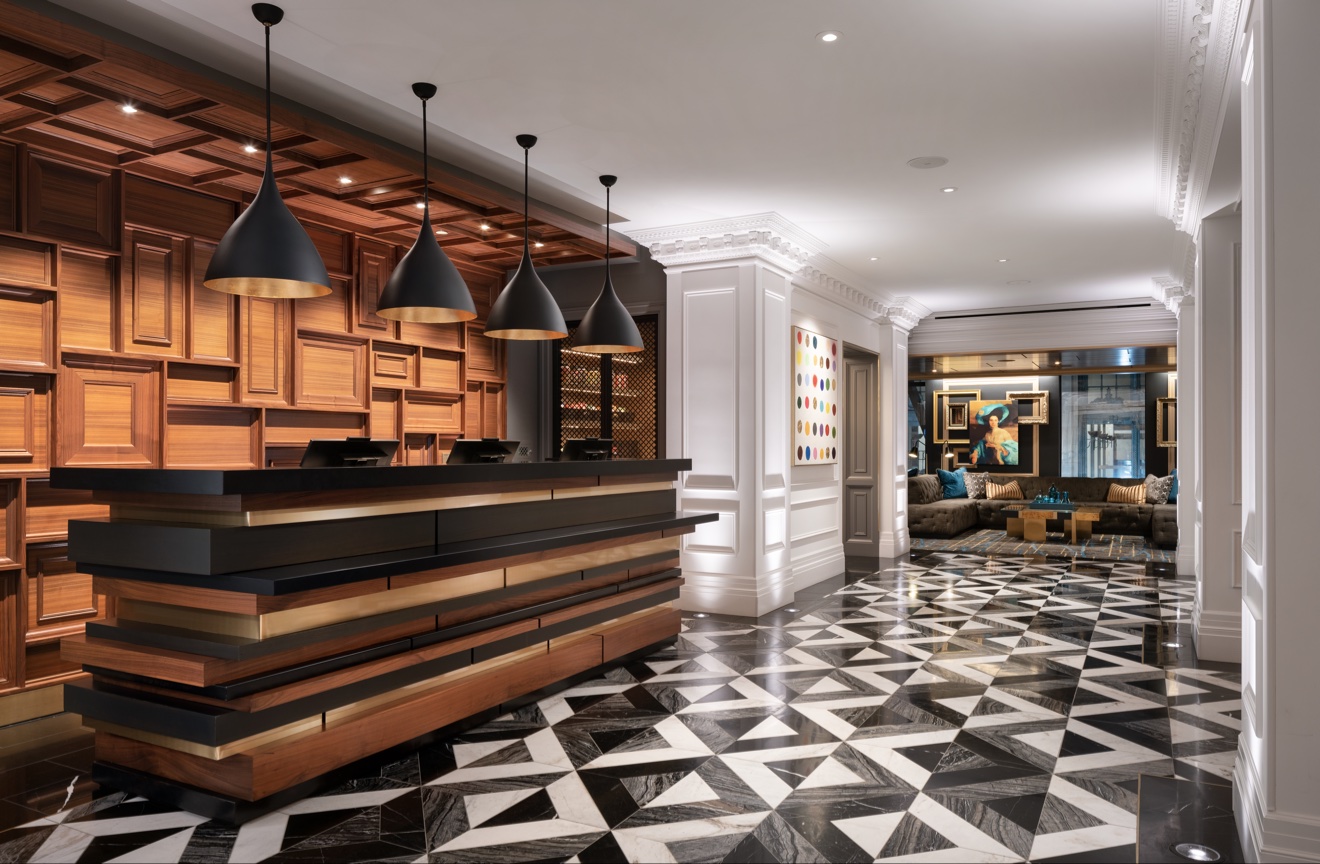 Hotel lobby with sculptural shelving, pendant lights, and patterned stone floor