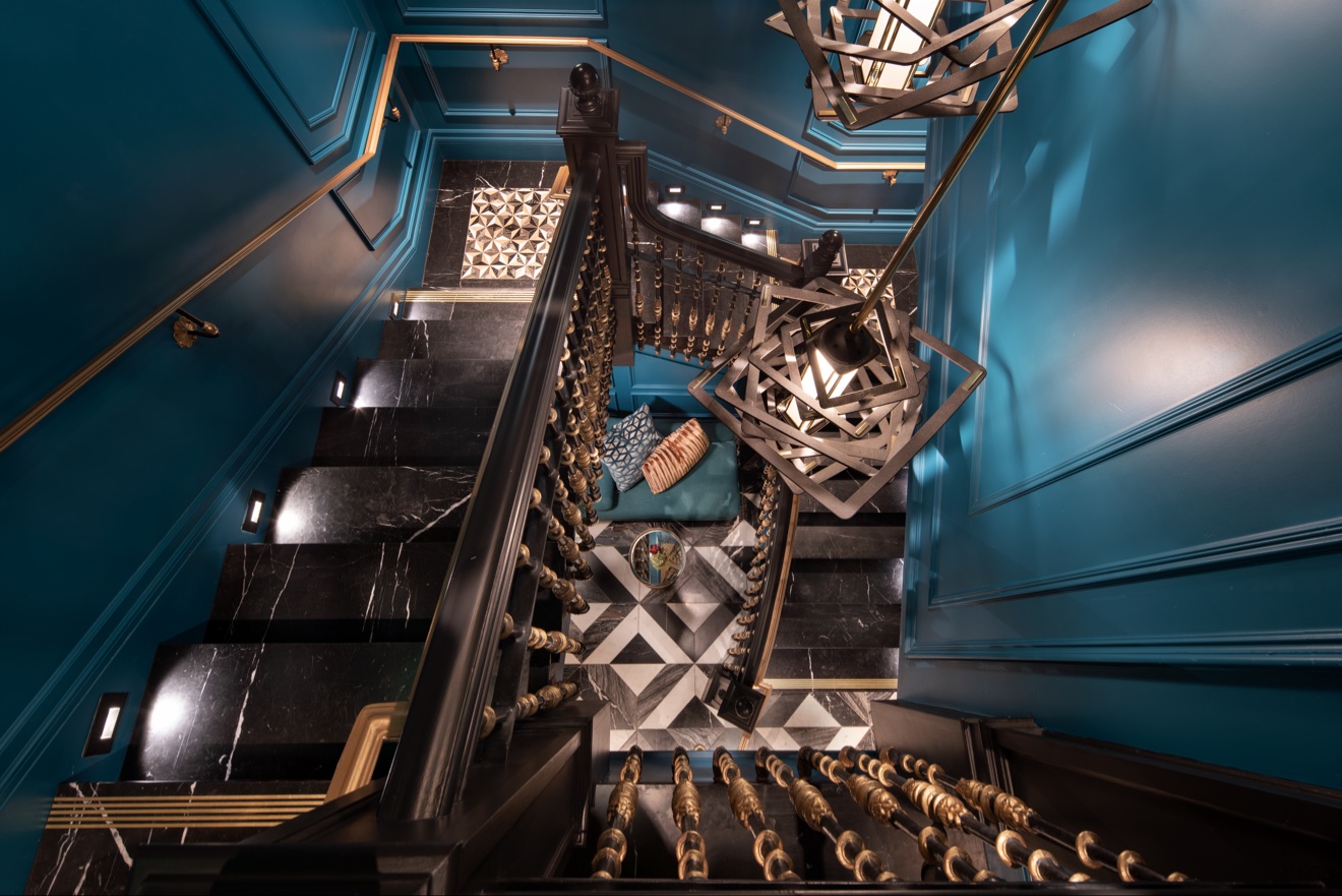 Teal-painted stair hall with ornate pendant lights and patterned floor