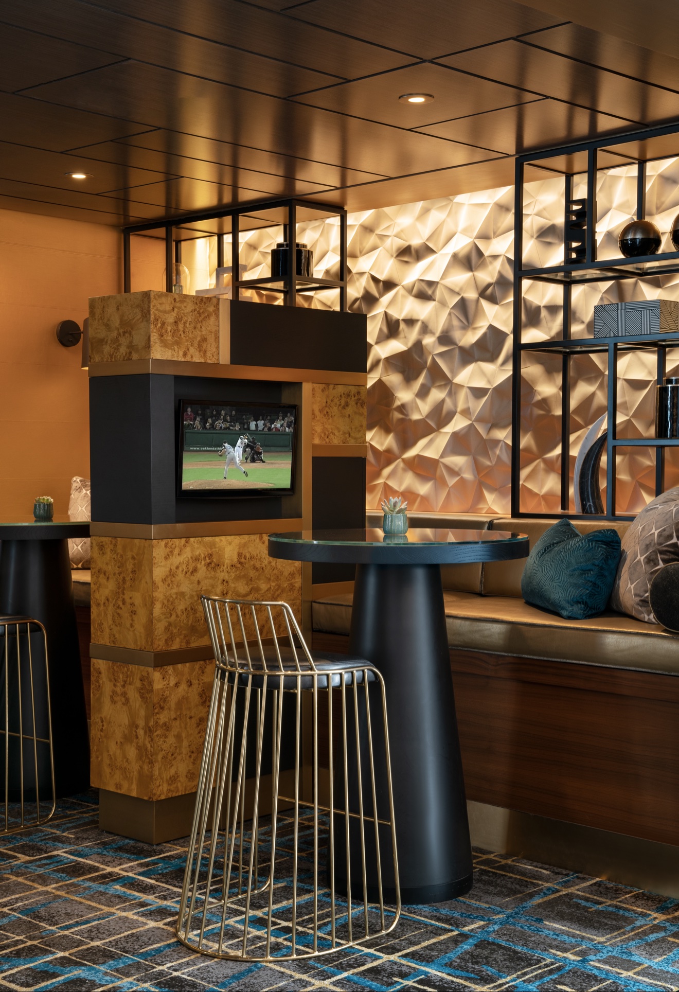 Compact hotel bar with faceted metal wall and built-in banquette