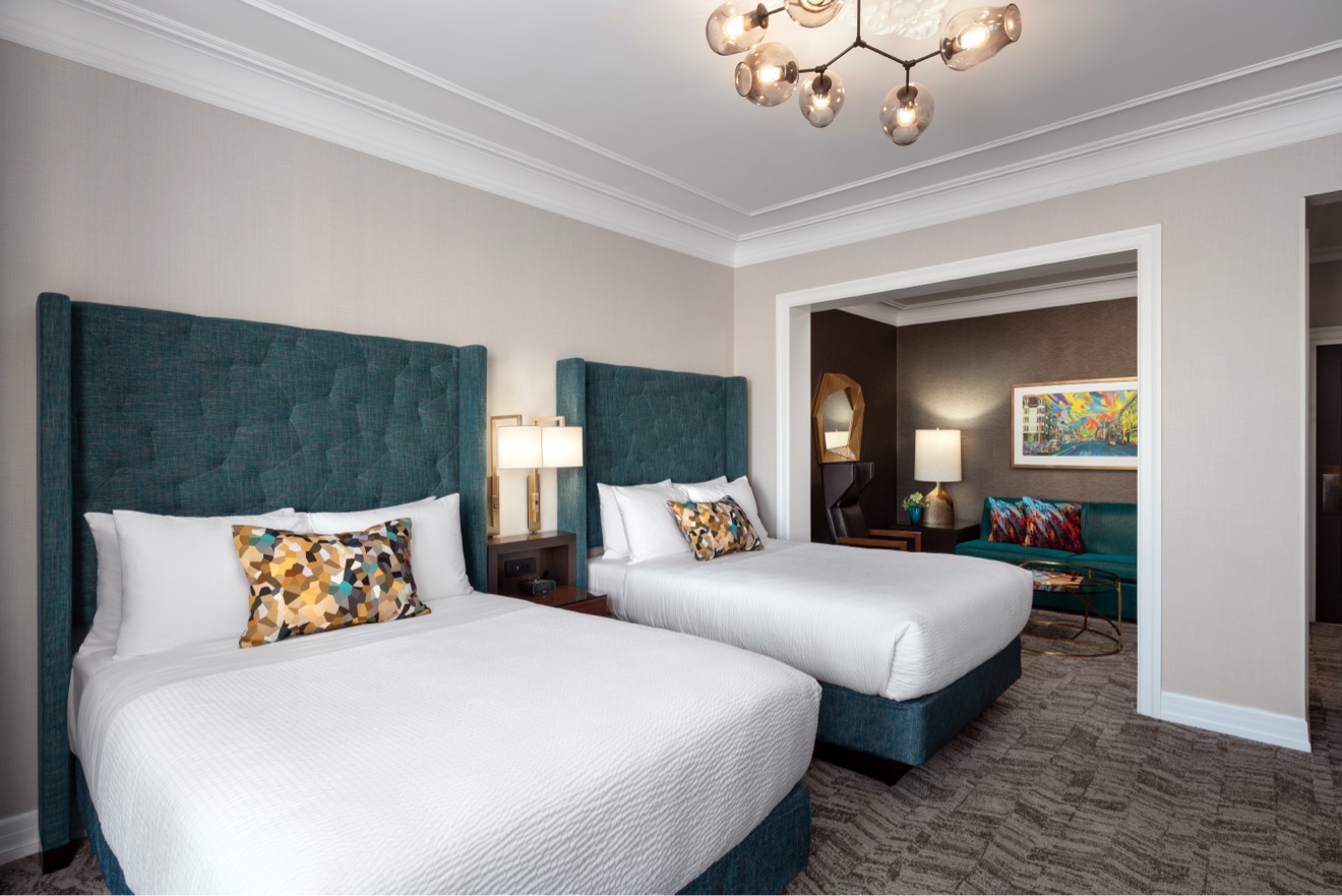 Double guest room with teal headboards and adjoining sitting room