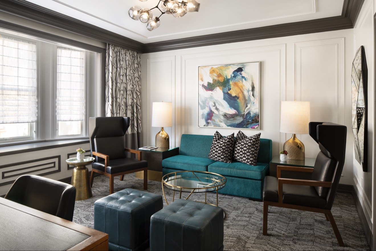 Guest suite sitting room arranged around teal seating and marble tables