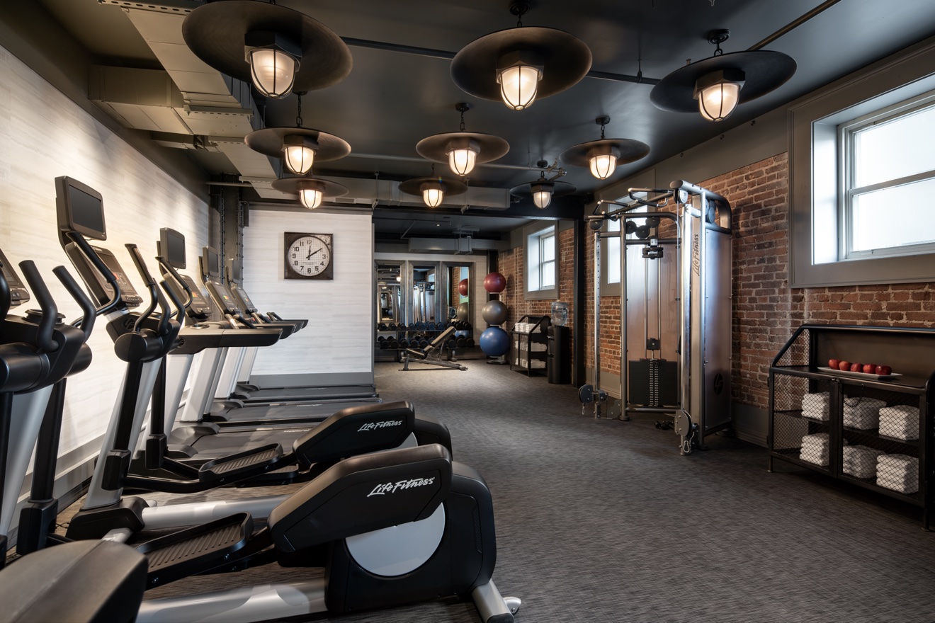 Hotel fitness center with cardio equipment and industrial ceiling lights