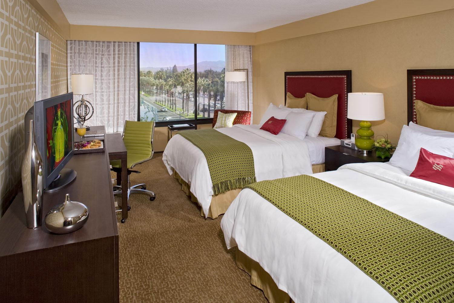Guest room with warm wood furnishings, patterned carpet, and red accents