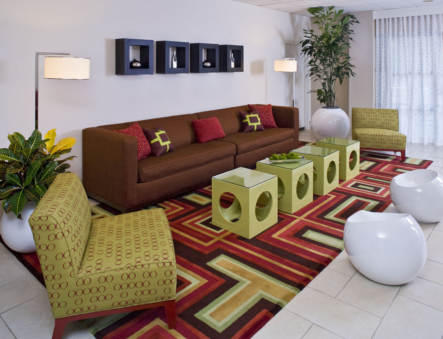 Guest room with a green upholstered bed and patterned red lounge chair