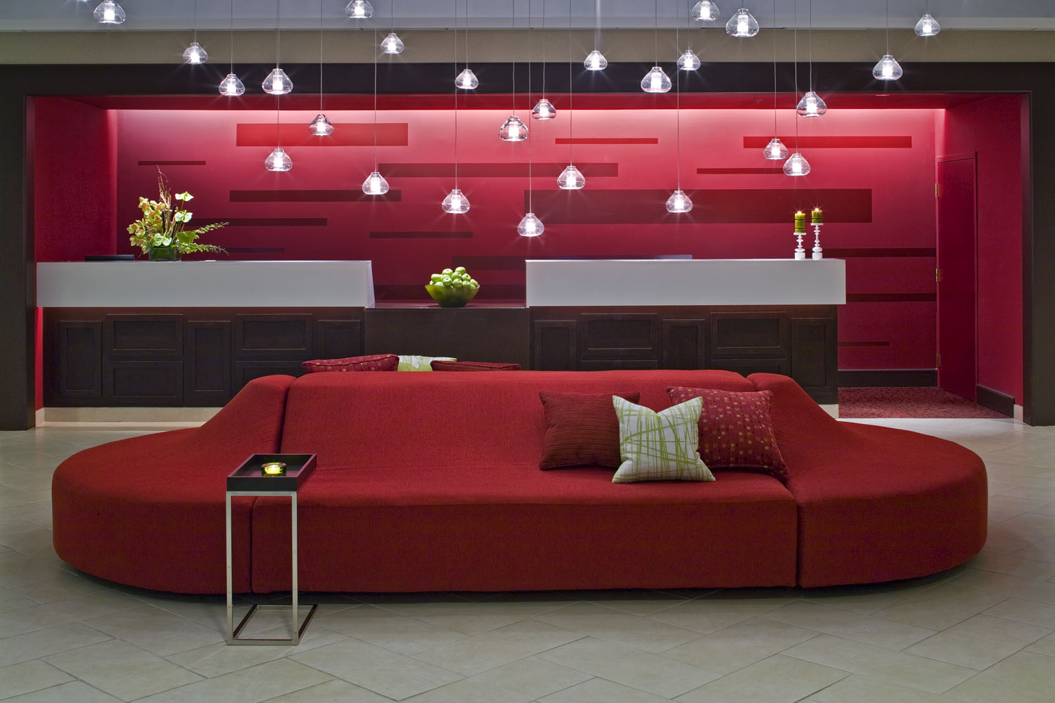 Hotel bar framed by red banquette seating and linear pendant lights