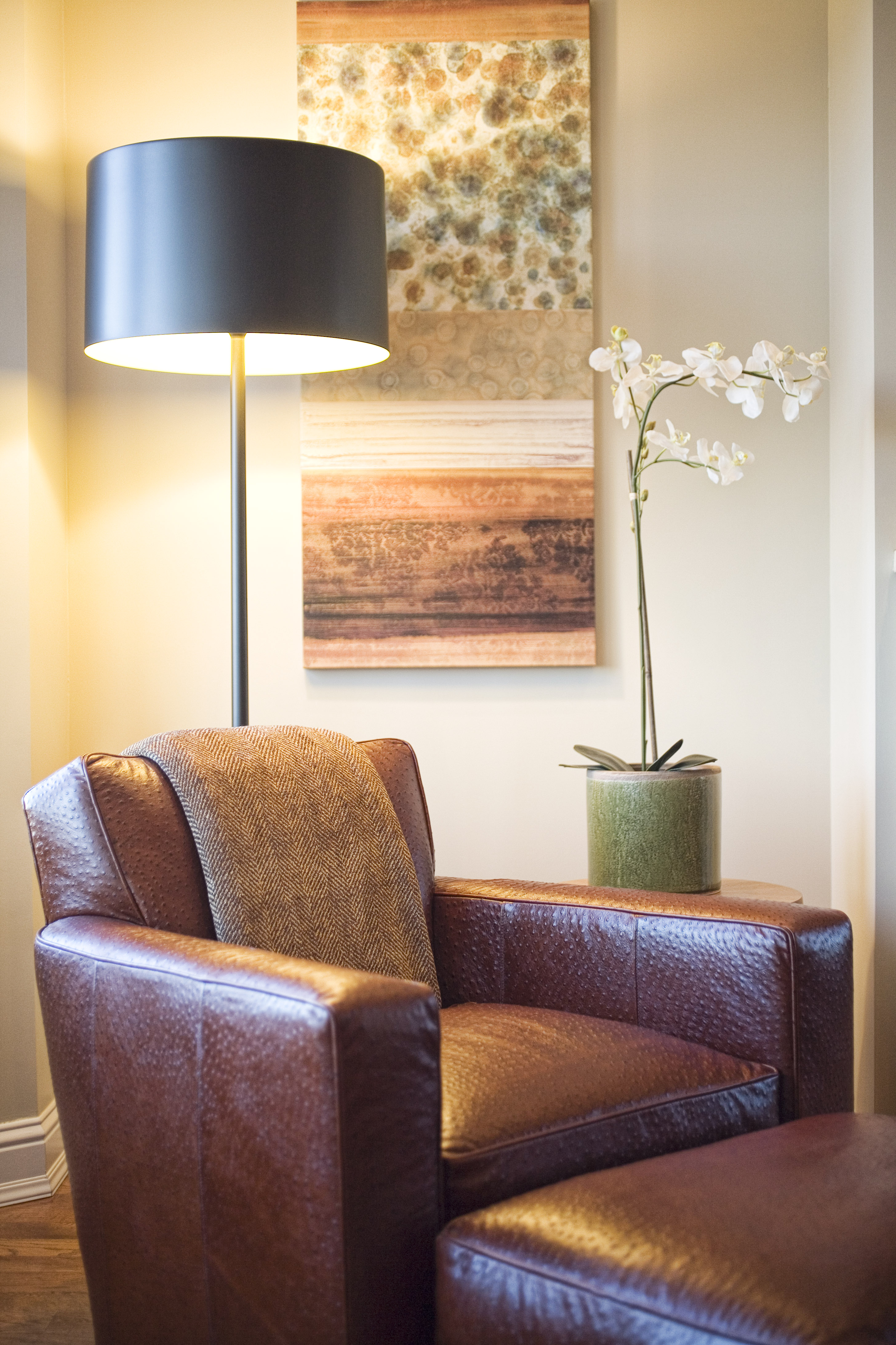Green Street A Residence leather armchair beside a floor lamp and flowering branch