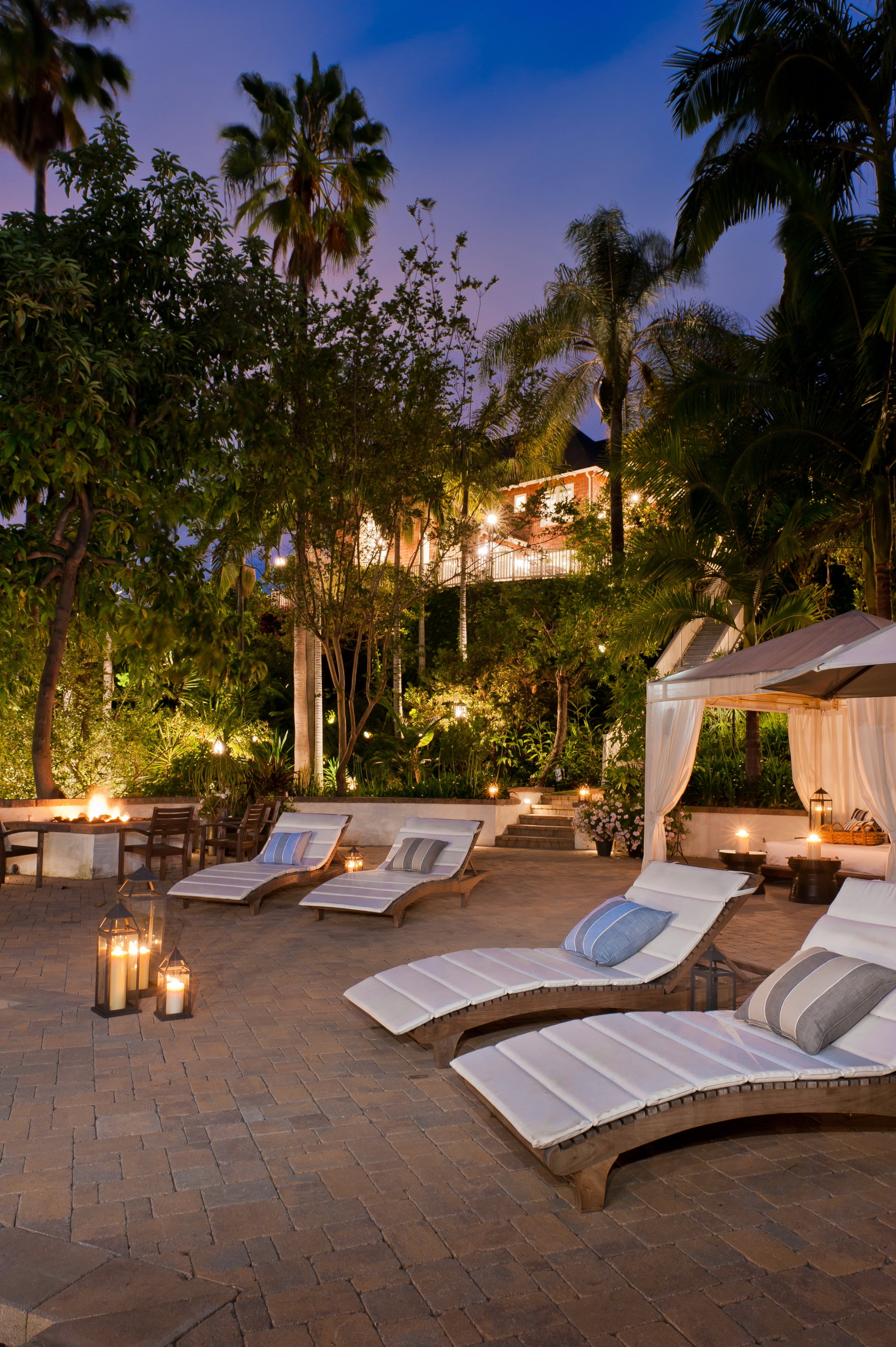 Evening garden terrace with lounge chairs, a cabana, and candlelight