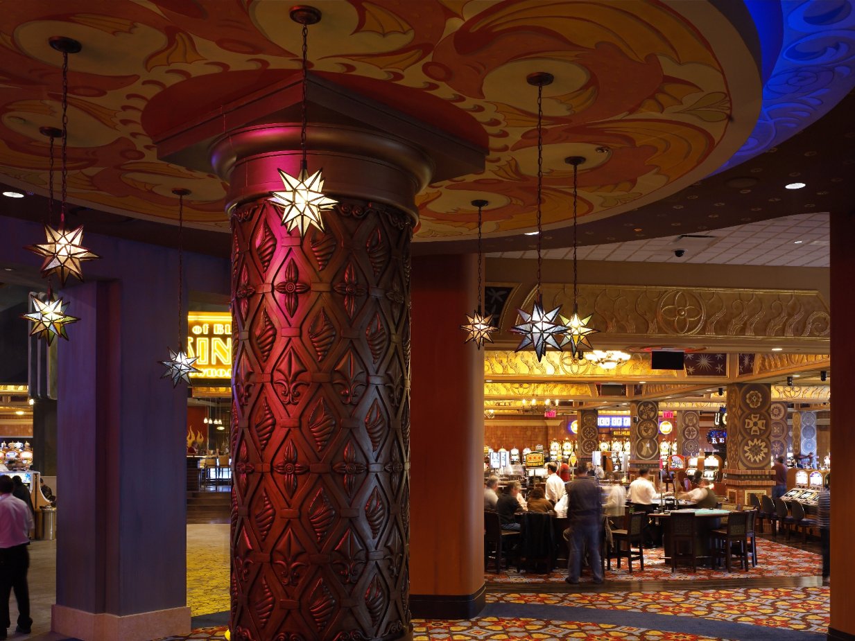 Casino floor framed by carved columns, star pendants, and patterned ceiling panels