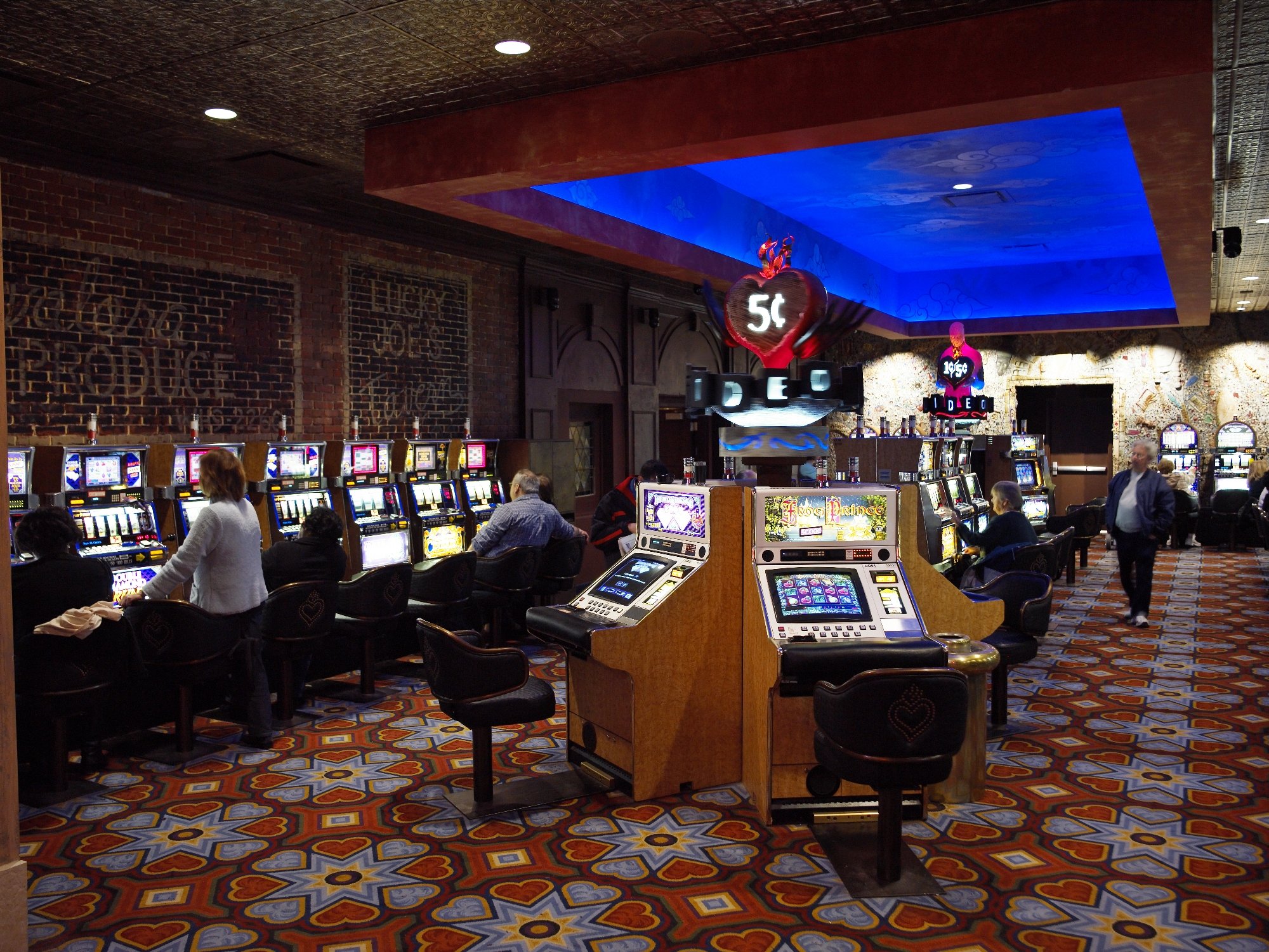 Casino slots area with vivid patterned carpet and blue ceiling lighting