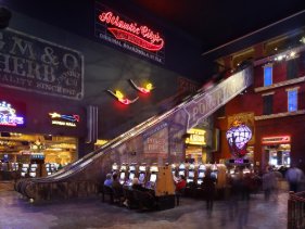 Casino interior with escalator, gaming floor, and illuminated signage