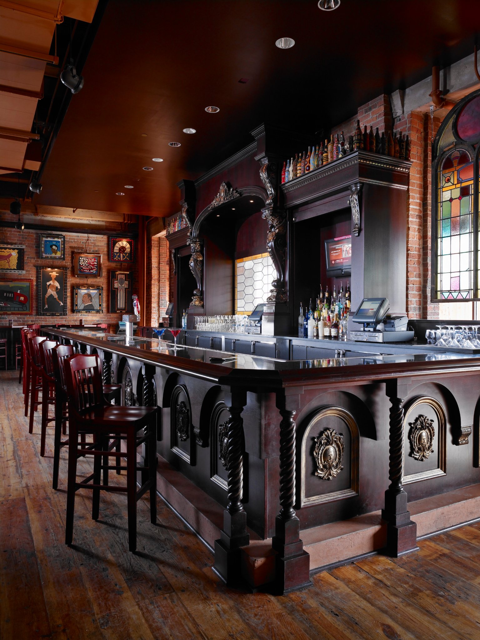 Ornately carved restaurant bar lined with dark wood stools