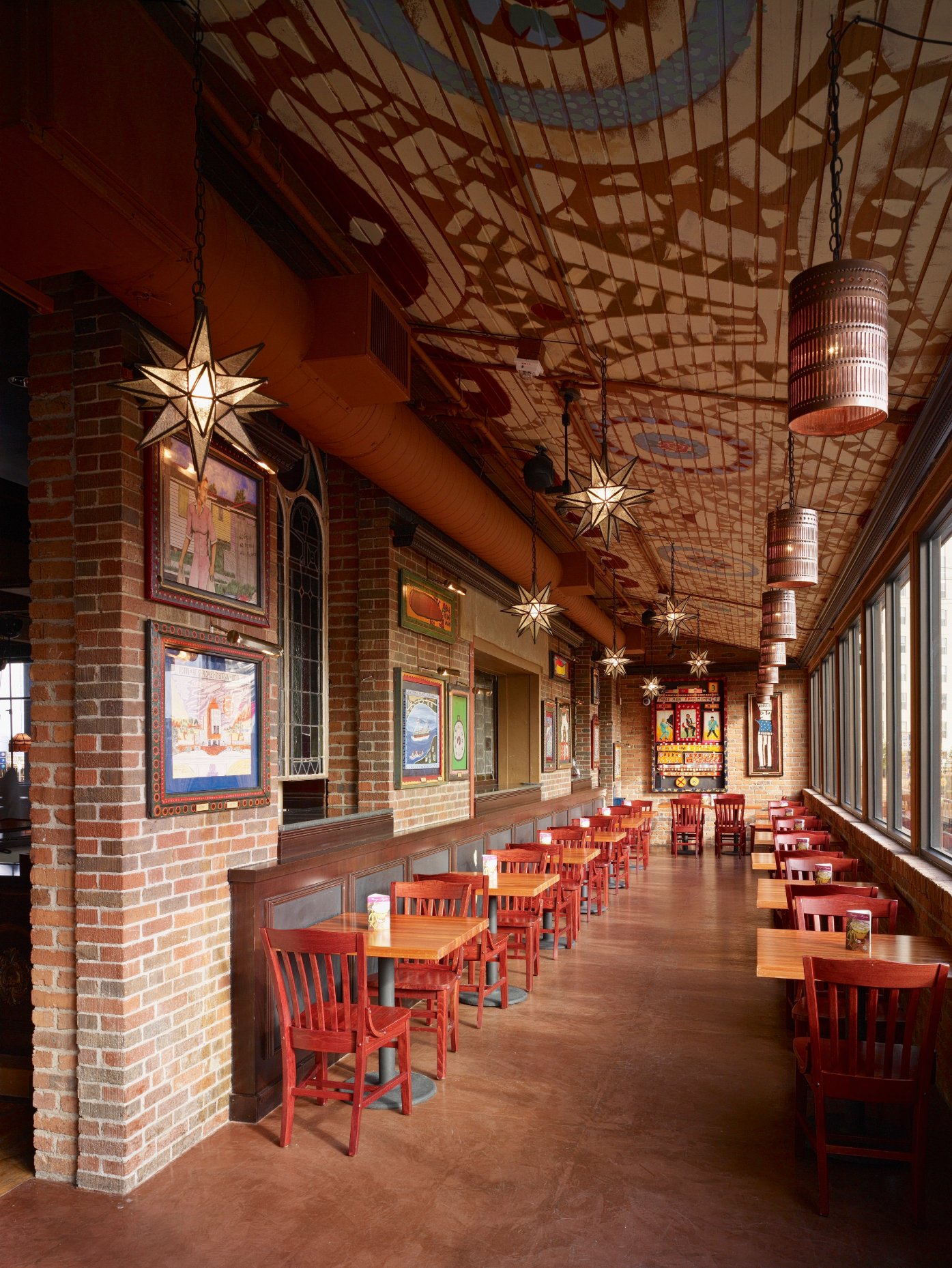Long restaurant dining room with patterned ceiling and red seating