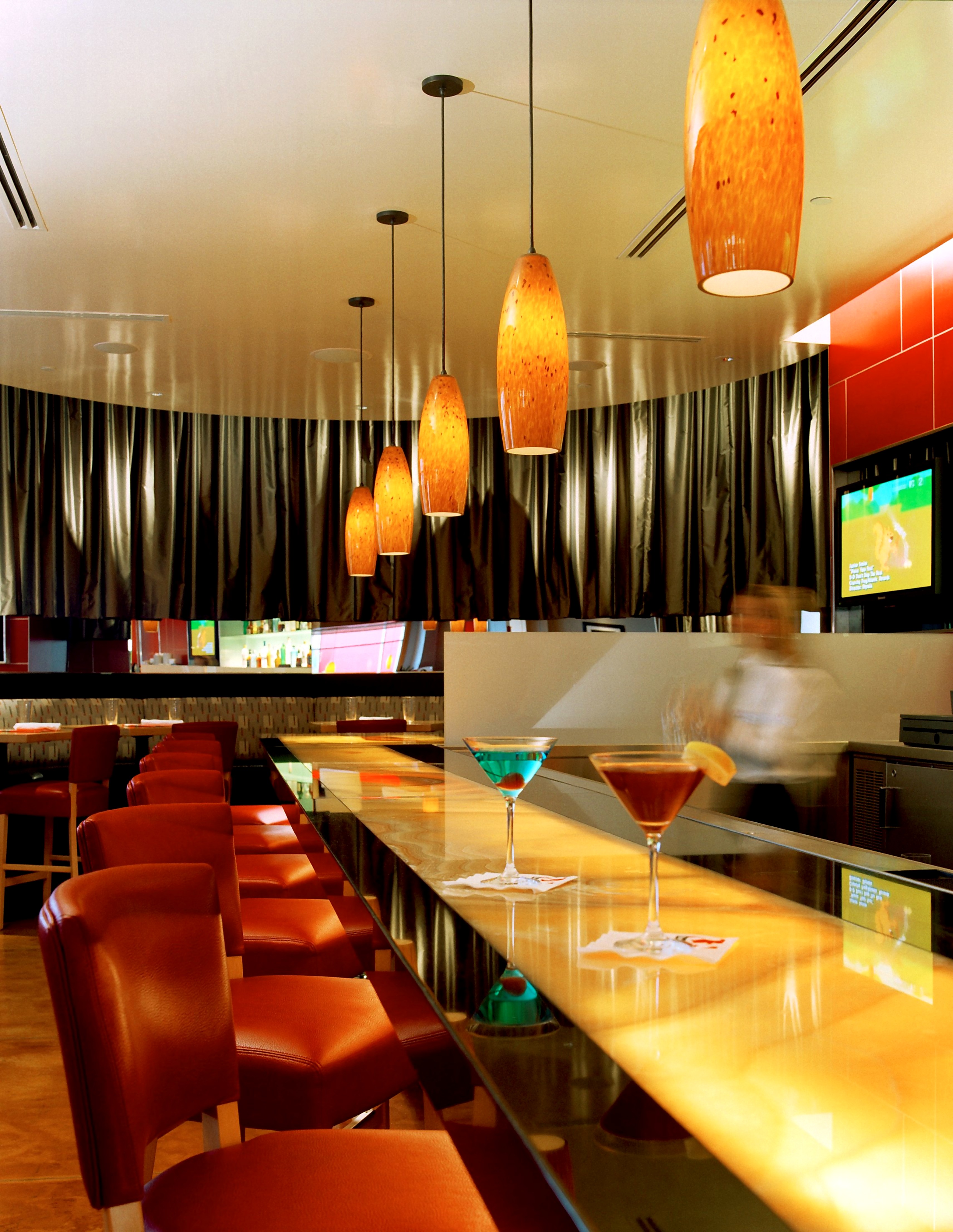 LA Food Show bar with glowing counter, colorful cocktails, and amber pendant lights