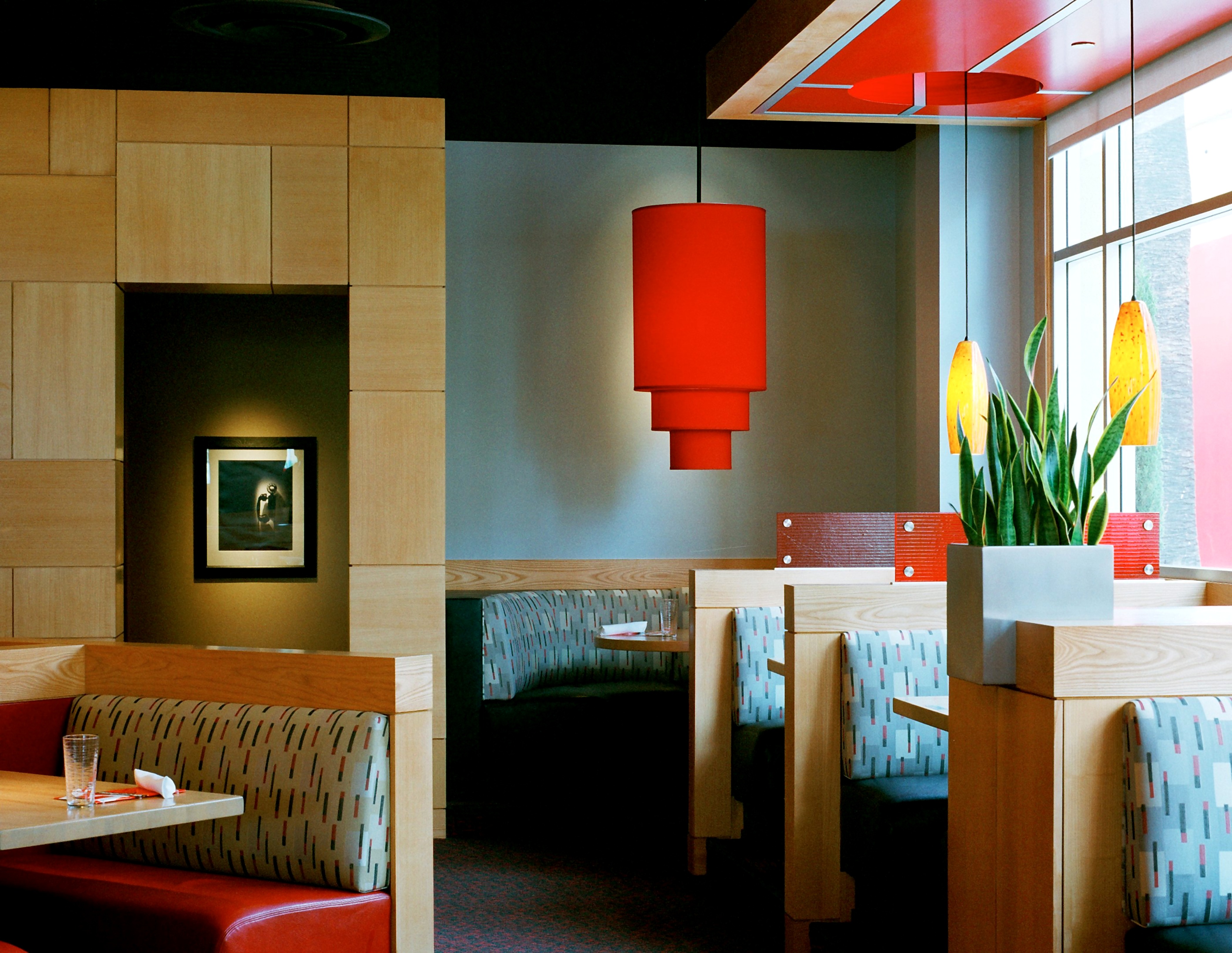 LA Food Show dining room with red pendant lights, warm woodwork, and upholstered booths