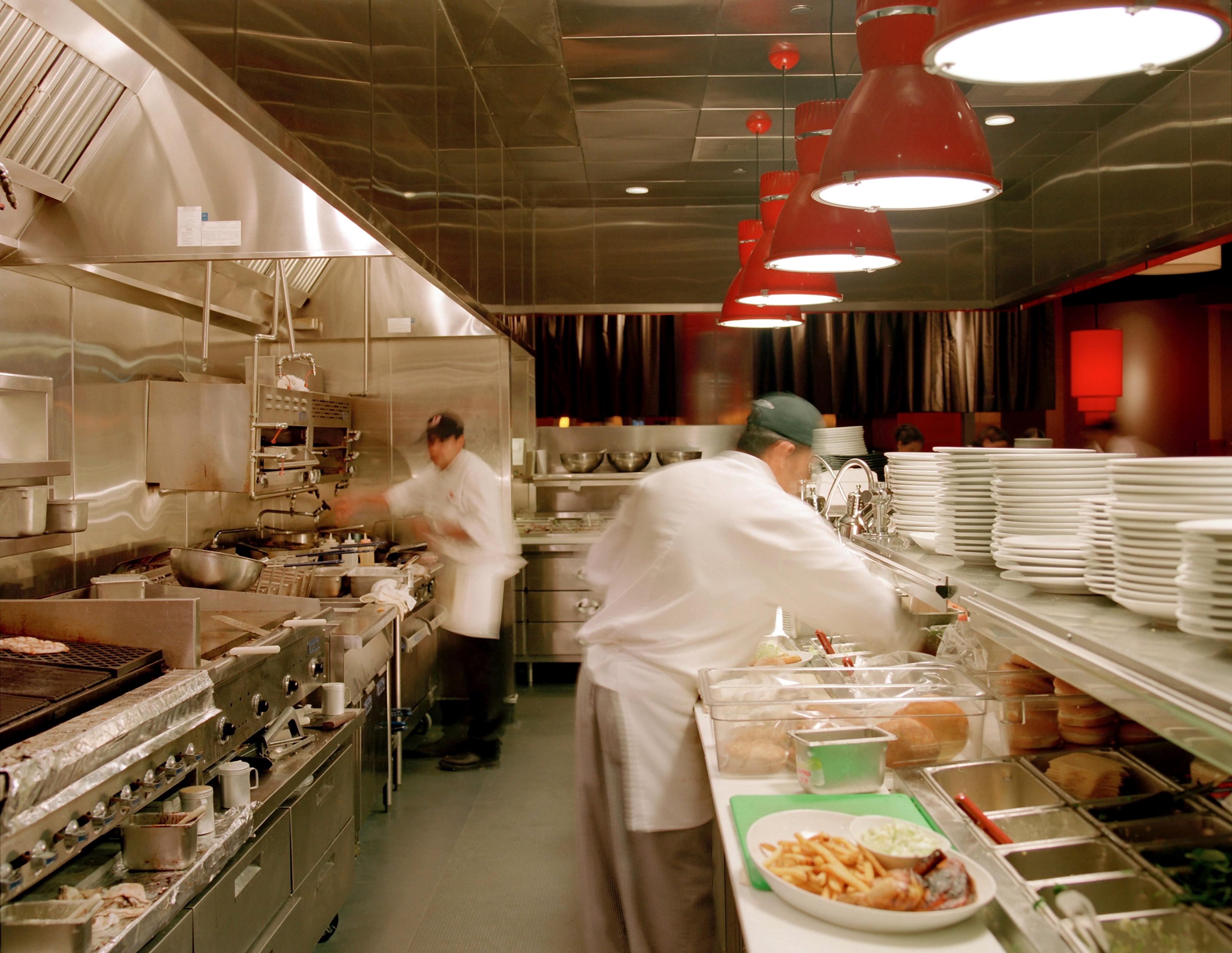 LA Food Show commercial kitchen with chefs at work beneath red heat lamps