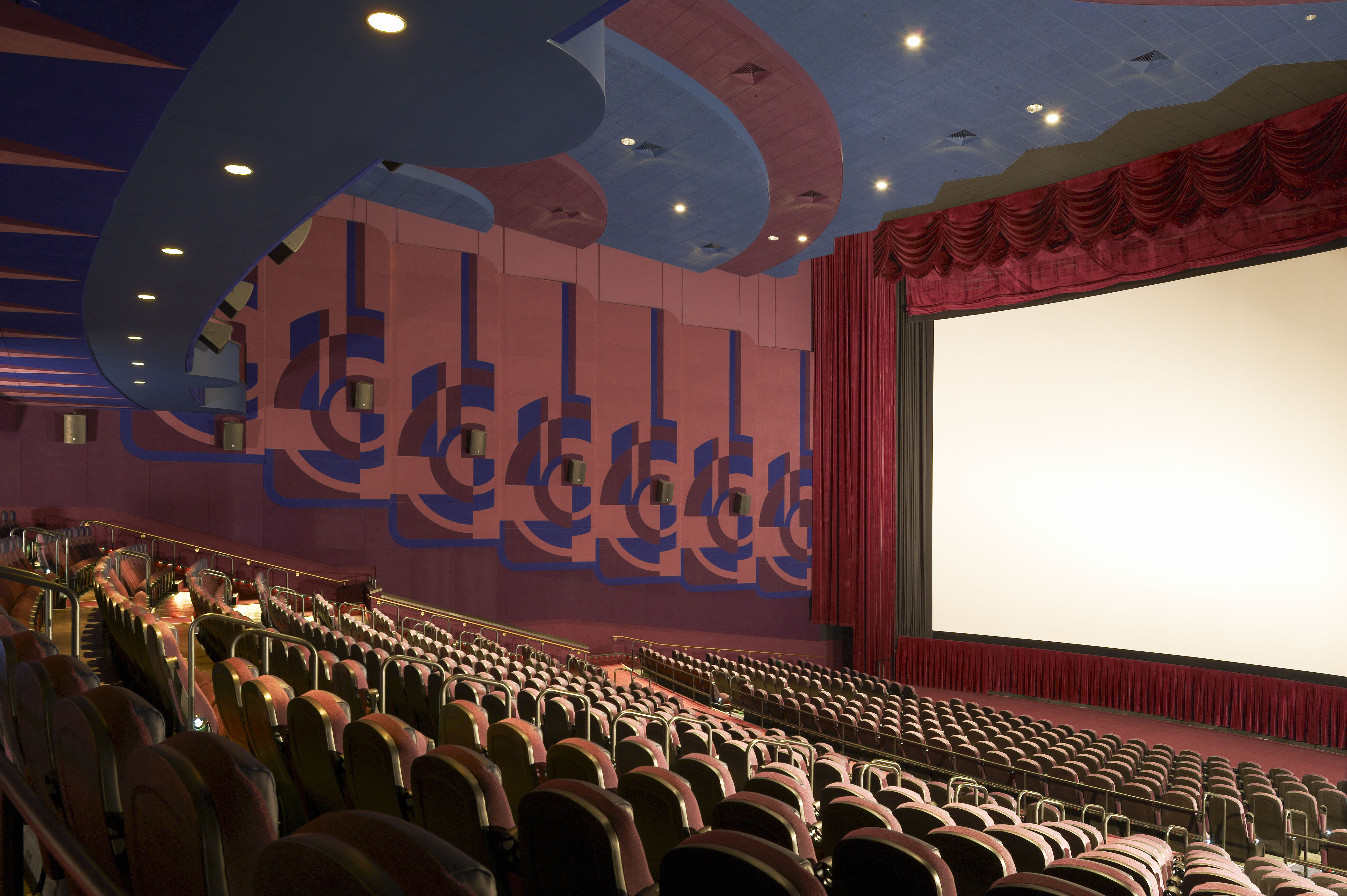 Auditorium with rows of seats, guitar wall motifs, and a red stage curtain