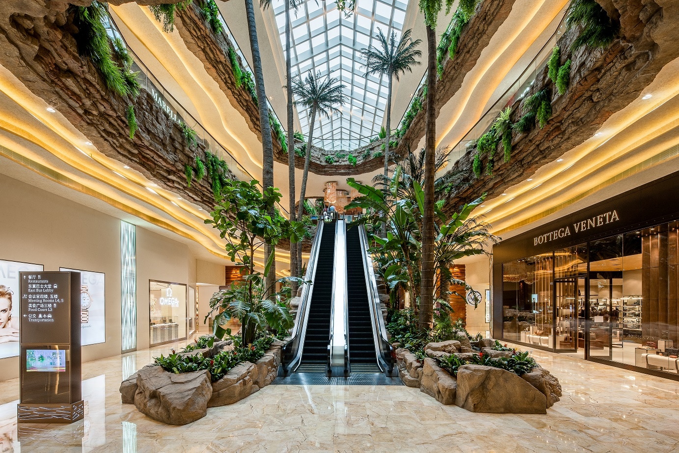 Atrium with escalators, palm trees, and a glass skylight