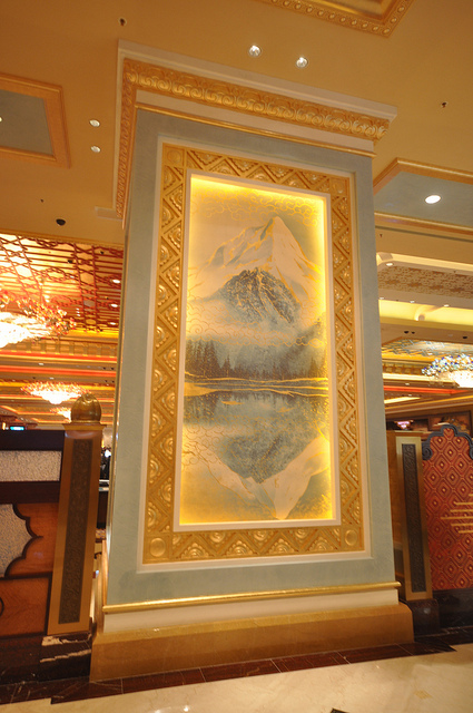 Illuminated mountain landscape artwork in a tall gilded frame