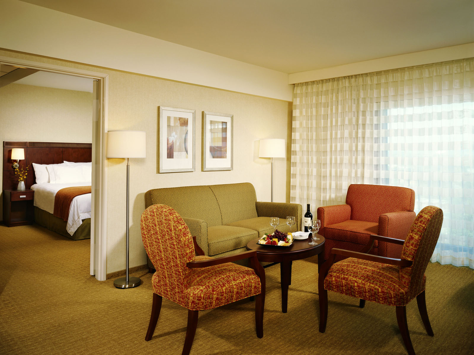 Suite sitting room with patterned armchairs, a sofa, and a view into the bedroom