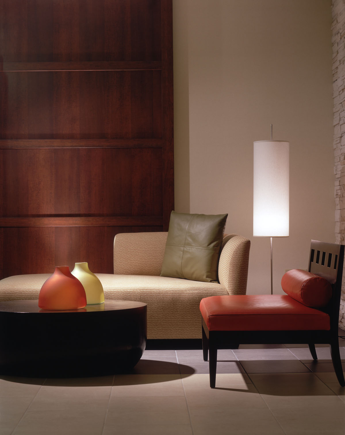 Lounge detail with a chaise, a red bench, and a floor lamp against walnut paneling