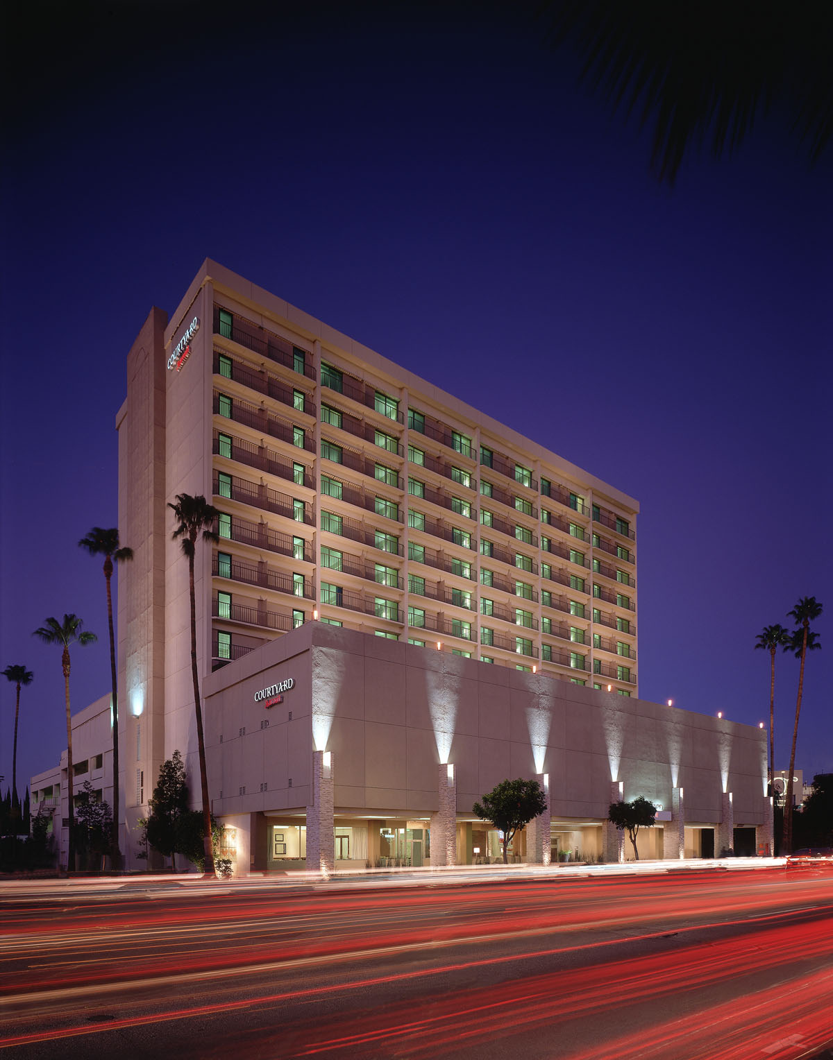 Hotel tower exterior at night above a street traced with light trails