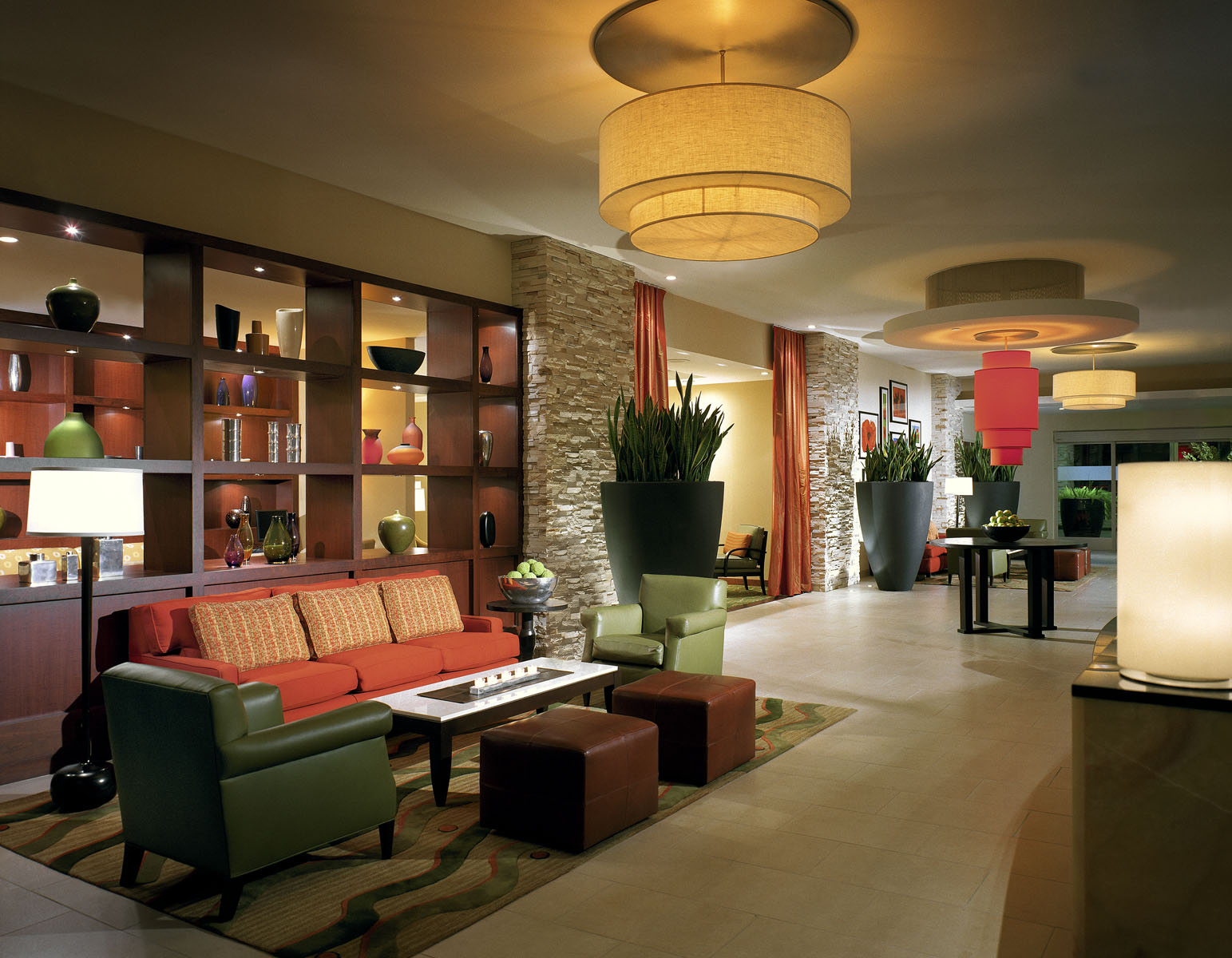 Lobby lounge with drum pendant lights, stone accents, and colorful seating