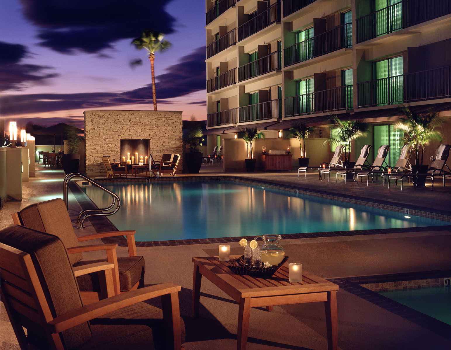 Courtyard Marriott Sherman Oaks pool deck at dusk with a stone fireplace and lounge chairs