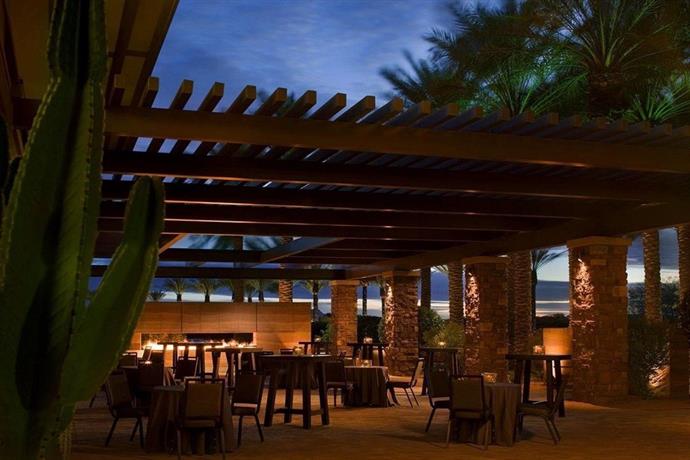 Outdoor resort dining terrace beneath timber pergolas at dusk