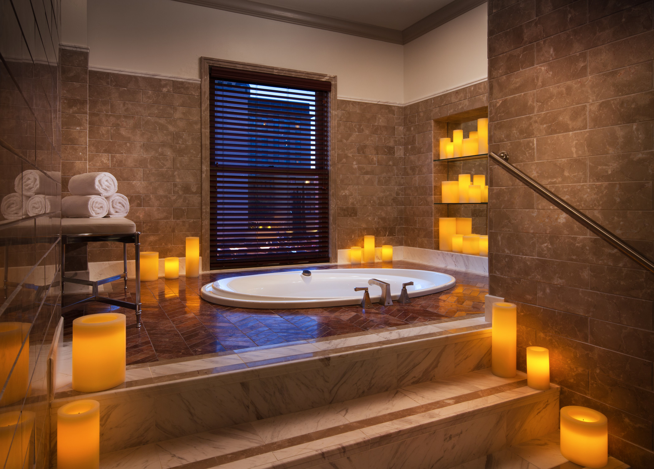 The Westin St Claire spa bath with a glowing stone wall, soaking tub, and candle niches